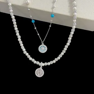 Vue détaillée du collier superposé avec pendentif boussole bleu, perles et cristaux.