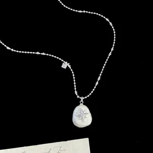 Detail showing a retro French irregular cotton pearl necklace with a starburst pendant.