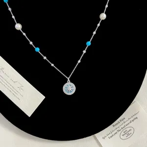 Gros plan d'un collier pendentif boussole en argent avec perles et billes bleues