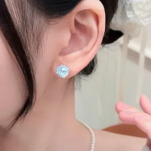 Primo piano di orecchini a lobo in zircone blu radiante su una modella asiatica.