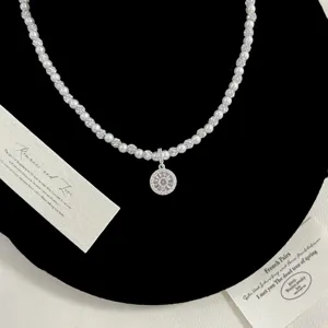 Détail macro du pendentif boussole de luxe avec zircon et collier de perles blanches