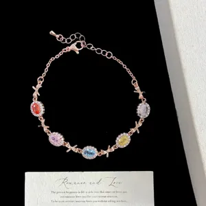 Primer plano de una pulsera de oro rosa con circonitas de colores y adornos de lazos.