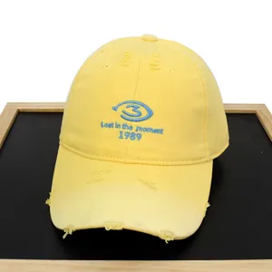 Detailed view of yellow distressed baseball cap featuring blue 1989 letter embroidery design