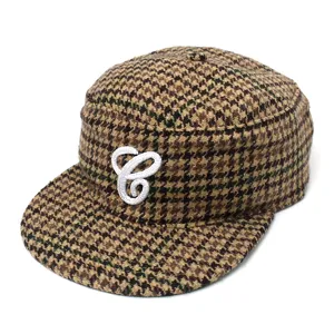 Nahaufnahme der modischen Karo-Flat-Cap mit auffälliger weißer Buchstabenstickerei.
