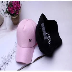 Detailed view of pink and black baseball caps with metal M logo and snapback strap
