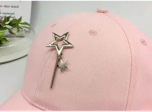 Macro detail of the silver metal star pendant attachment on a pink cotton baseball cap