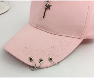 Macro detail view of a pink cotton baseball cap with metal rings and star pendant charm