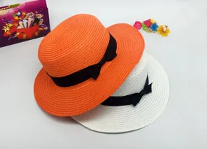 Close-up detail shot of summer straw hats with elegant black ribbons in orange and white colors.