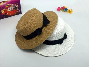 Detailed view of summer straw hat, flat top design with elegant black bow ribbon trim.