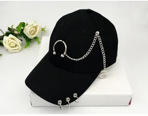 Detail of a black baseball cap featuring metallic chain, rings on brim, and horseshoe charm.