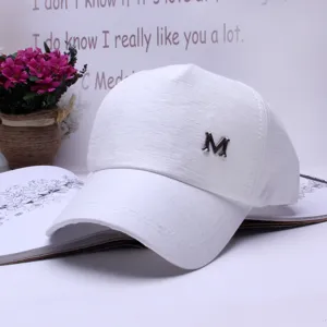 Stylish white baseball cap with metal M logo and curved brim for sun protection.