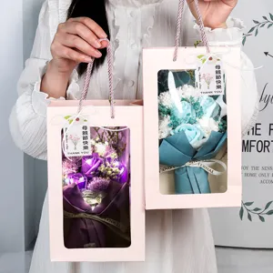 Elegantes ramos de flores de jabón en cajas rosa con cálidas luces LED decorativas