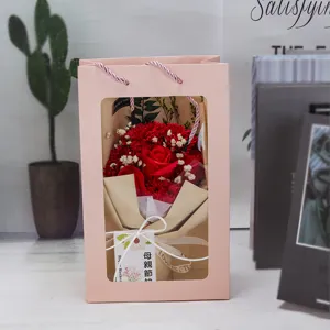Detalle de un ramo de flores de jabón rojas en una bolsa de regalo rosa con ventana