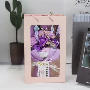 Detalle de ramo de rosas de jabón púrpuras y claveles en bolsa de regalo rosa para mamá.