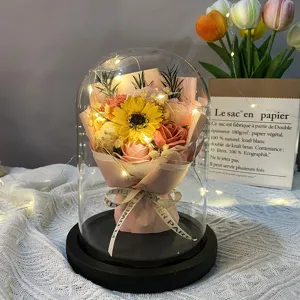 Detailed view of artificial soap flower bouquet with LED lights in a large glass dome