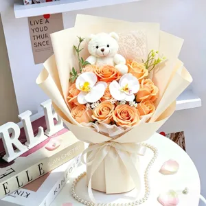 Oranger Seifenrosenstrauß mit weißem Teddybär und Orchideen als Geschenk im Detail.