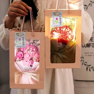 Detalle de ramos de flores de jabón rosa y rojo en bolsas de regalo con luces LED cálidas