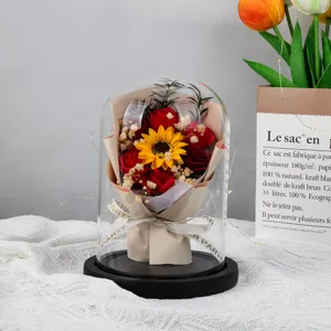 Close-up view of a large glass dome night light with soap roses and a sunflower