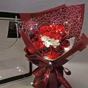 Detailed close-up view of a romantic red soap flower bouquet decorated with fairy lights and ribbon.