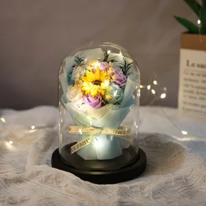 Close-up of artificial soap flower bouquet in a glass dome with LED fairy lights