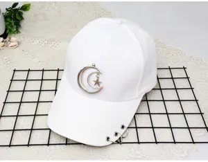 White baseball cap detail showing the metal crescent moon star pendant and brim rings design.