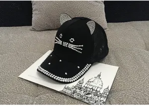 Close-up of rhinestone cat ears and whiskers on a black mesh baseball cap