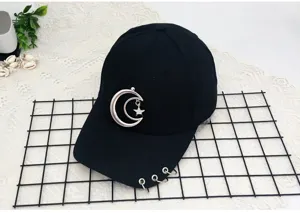 Detail shot of black baseball cap with metal moon star pendant and brim rings decoration.