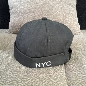 Close-up view of the dark grey brimless cap featuring neat white NYC embroidery and quality texture.