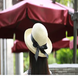 Detailed rear view of a stylish beige straw sun hat with elegant black bow ribbon