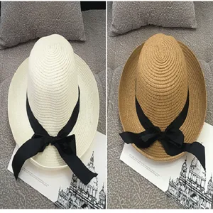 Detail view of wide brim straw sun hats with black ribbon bows in white and tan colors.