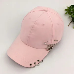 Pink cotton baseball cap with decorative metal rings and a stylish safety pin charm