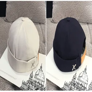 Detailed view of trendy brimless miki hats with embroidered X logo, stylish docker cap design.