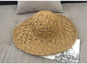 Detail of hand-woven straw sun hat with wide wavy brim for summer beach vacation