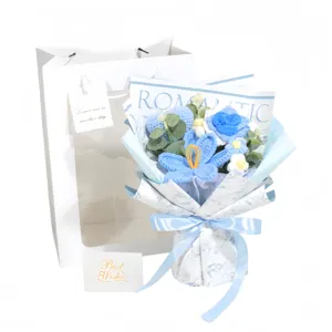 Detailed shot of a handmade blue knitted flower bouquet with white gift bag and card.