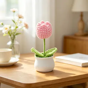 Handmade crochet pink tulip potted plant on a wooden desk with soft sunlight