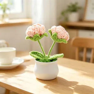 Close-up of two delicate hand-crocheted potted pink flowers on a sunlit wooden table.