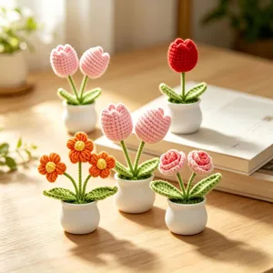 Handmade crochet flowers in white ceramic pots displayed on a cozy wooden desk