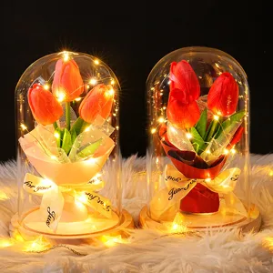 Detalle de dos elegantes cúpulas de vidrio con tulipanes y luces LED sobre piel blanca