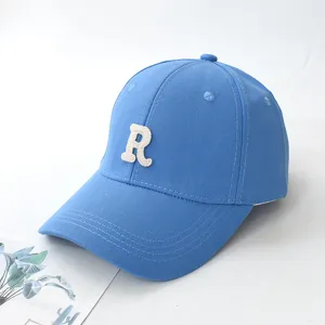 Close-up detail shot of a stylish blue baseball cap featuring a white embroidered letter R design
