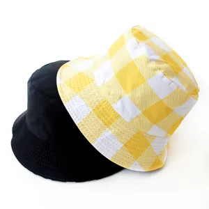 Detail of a yellow checkered and solid black reversible bucket hat on a white background.
