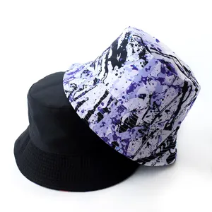 Close-up detail of a reversible bucket hat showing solid black and purple ink splash.