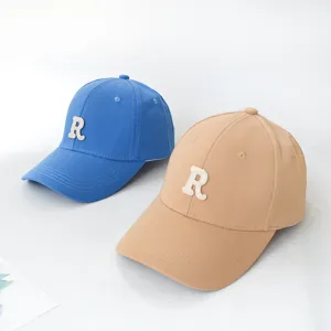 Two stylish baseball caps in blue and khaki colors with white letter R patch on the front