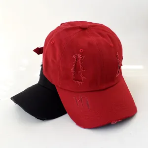 Close-up detail of distressed ripped baseball caps in red and black, trendy casual style.