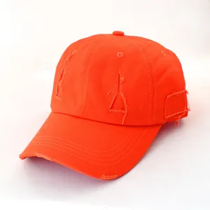 Close-up detail of the orange distressed baseball cap showing ripped design and curved brim.