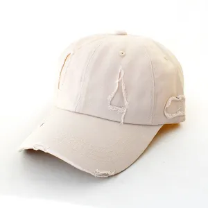 Detailed view of beige distressed baseball cap, cotton fabric with ripped design, summer hat.