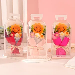 Detail view of three hand-knitted sunflower smiley bouquets in clear PVC gift boxes