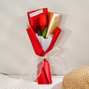 Gedetailleerd overzicht van kunsttulp bloemenboeket cadeau verpakt in rood papier met strik.