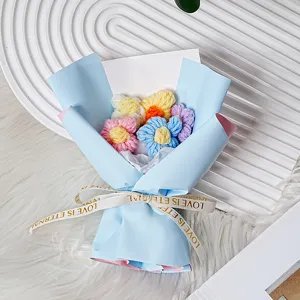 Vista detallada del ramo de flores de ganchillo hecho a mano en papel azul con cinta.