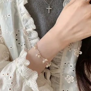 Primer plano de una delicada pulsera de perlas de estilo francés con dijes en la muñeca.