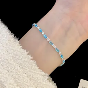 Close-up of a silver bracelet with alternating blue rectangular and white round zircons.